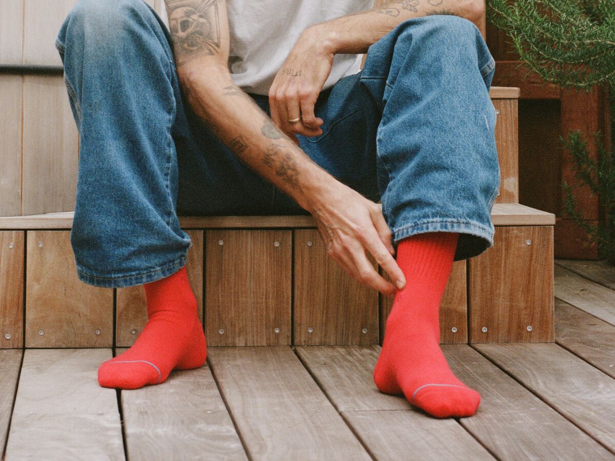 image of red icon socks on a model sitting on a wooden bench.
